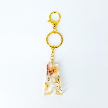 Porte clés personnalisé en résine la lettre A avec fleurs naturelles et feuille d'or fait main par Ryn Handmade حاملات المفاتيح بالرزين مصنوع يدويا بازهار طبيعية و ورقة دهببية's image